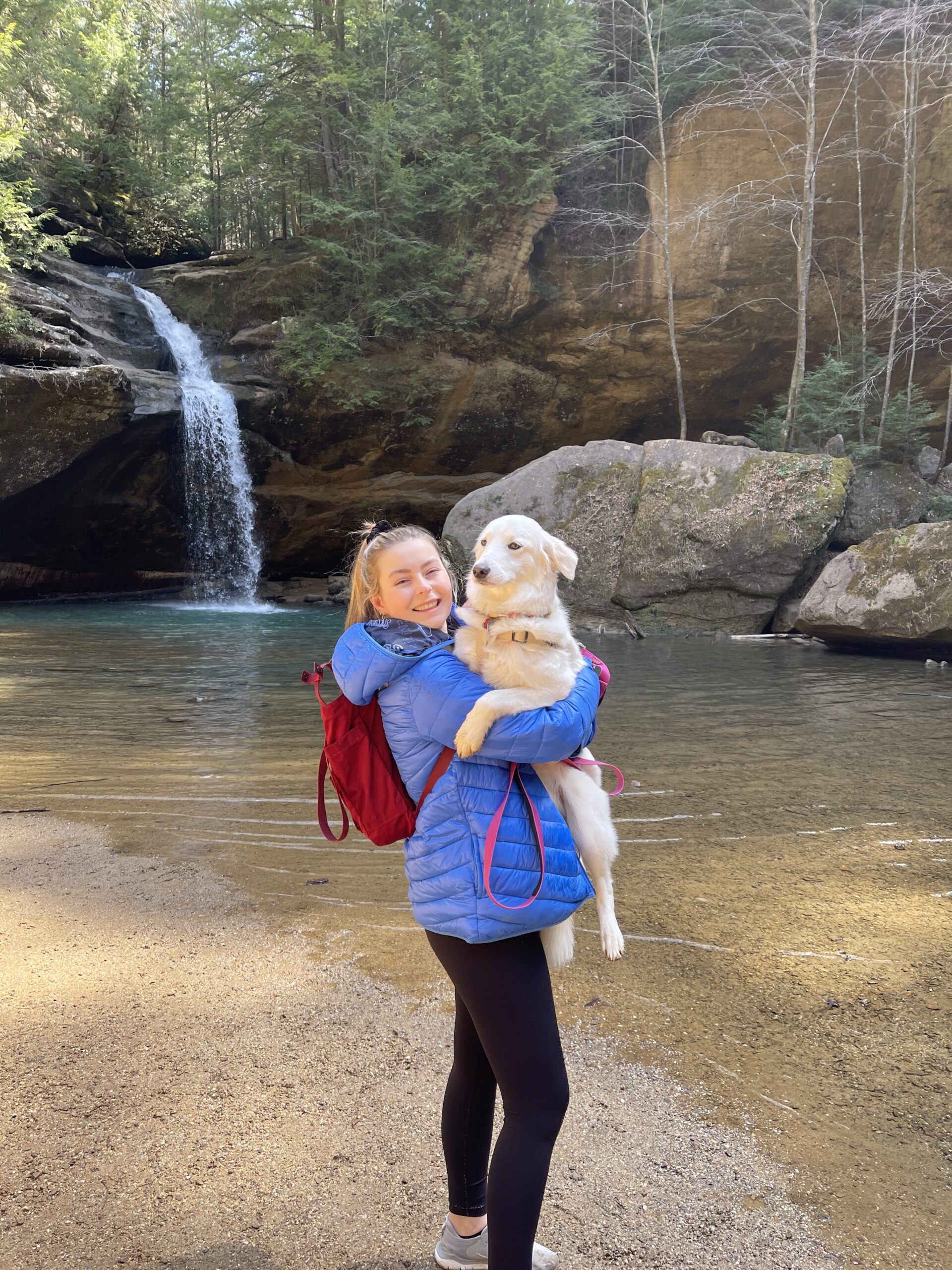 A photo of Ashton Nichols and her dog, Nilla in front of a waterfall