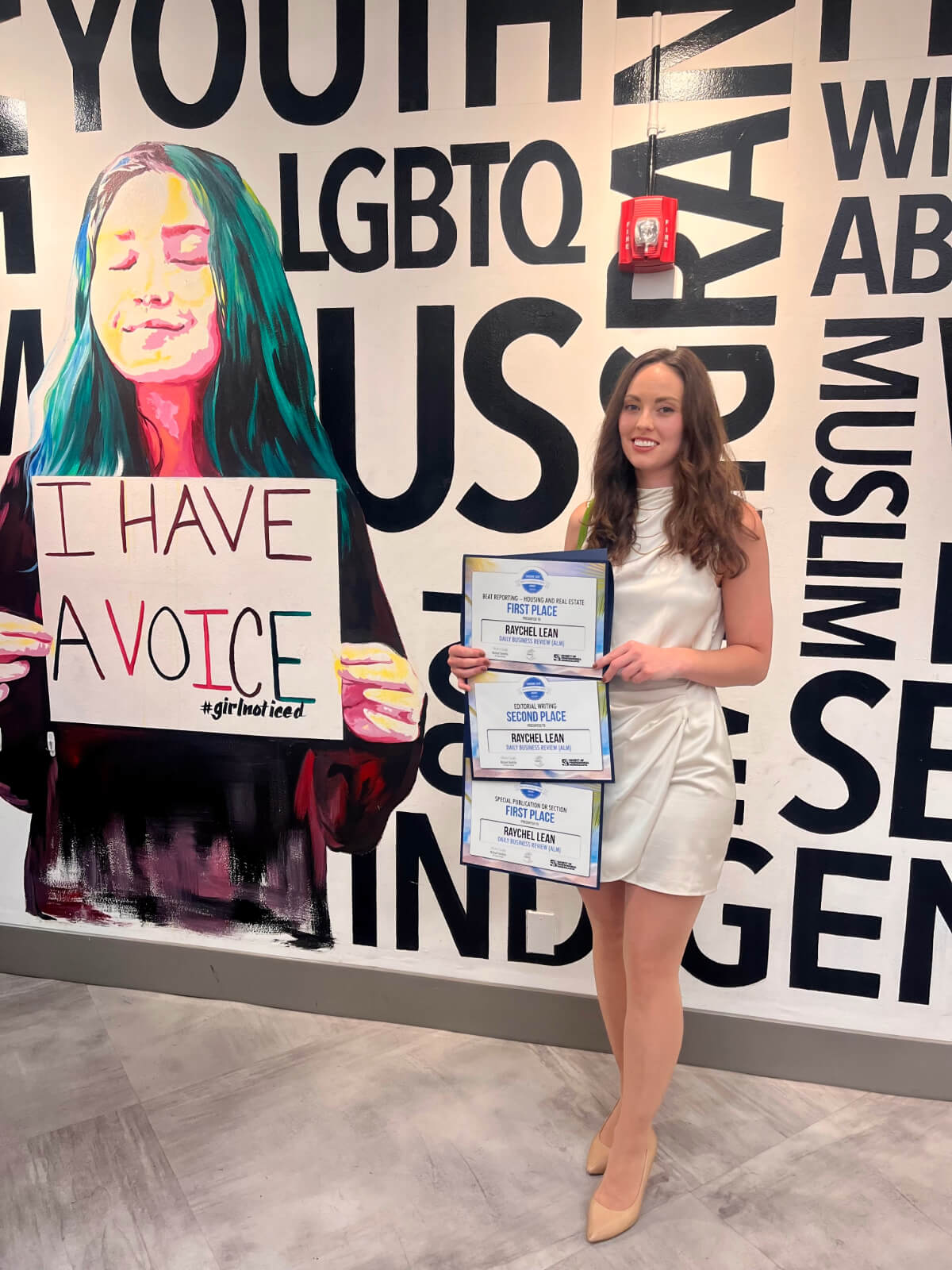 Raychel Lean standing with three awards from the Society for Professional Journalism Florida.