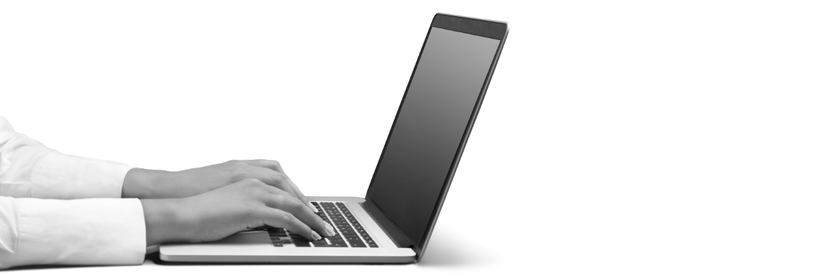 A black-and-white image of a professional typing at a laptop computer