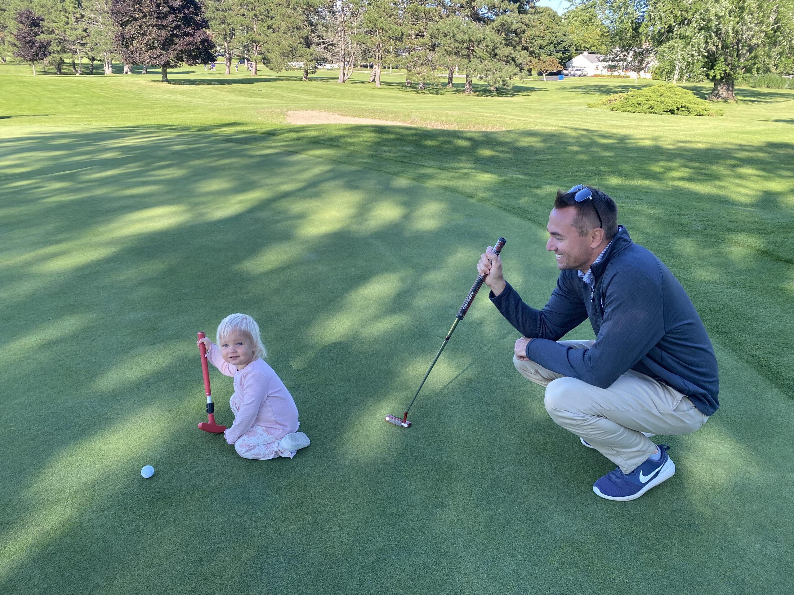 A dad and toddler on a golf course