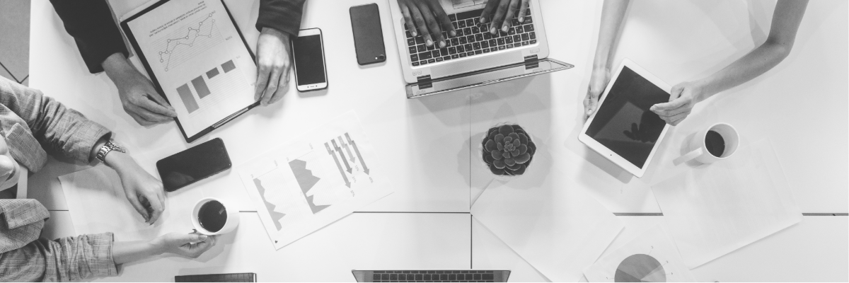 Graphic of workplace table top with computers and people working