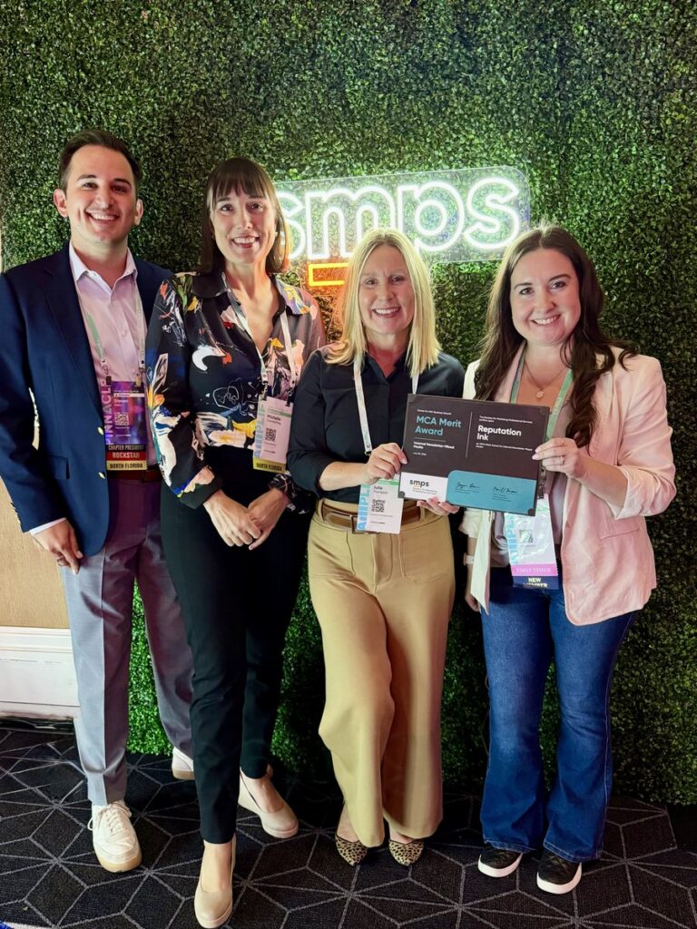 Reputation Ink team and partners holding the 2026 SMPS MCA Merit Award plaque for Superior Construction’s FamilyFirst bilingual employee newsletter at the Amplify A|E|C conference in Las Vegas